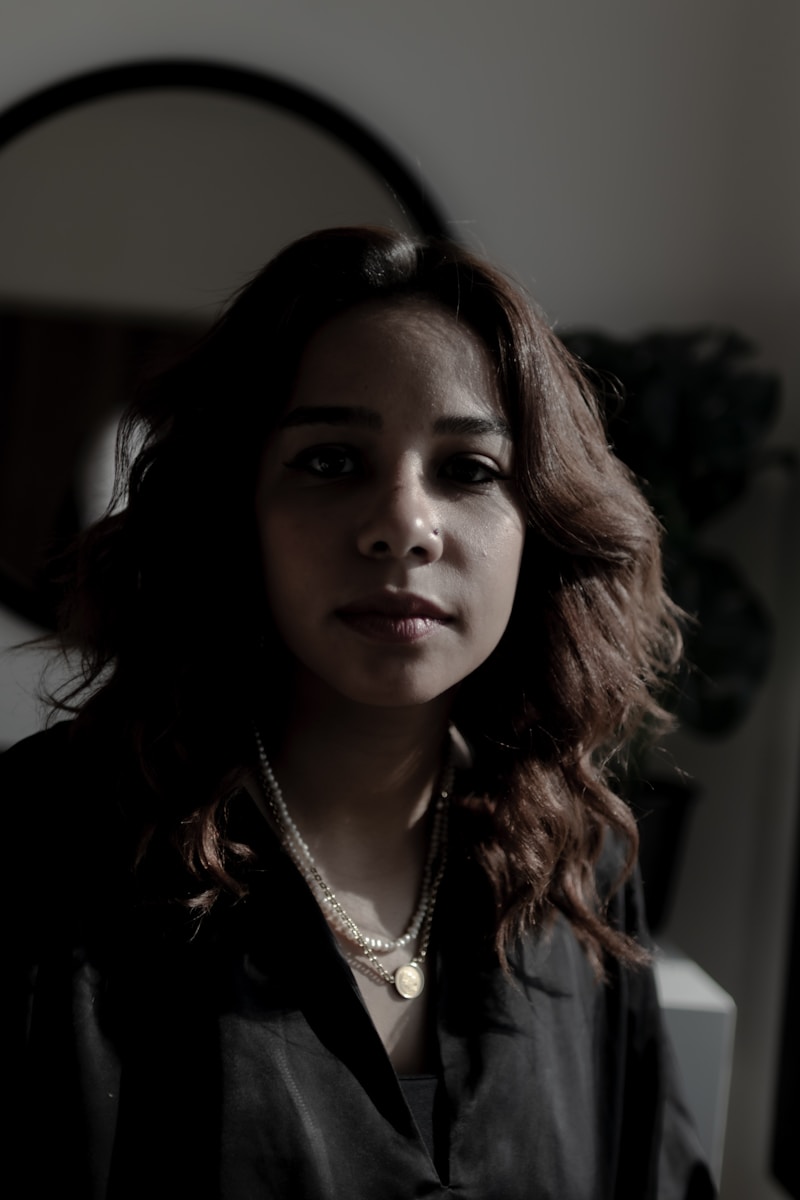 A woman in a black shirt looking at her reflection in a mirror